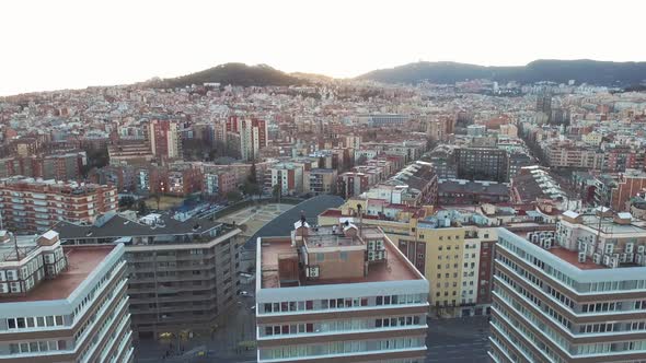 Aerial view of three buildings in a big city with people on the rooftop. Forward camera movement.