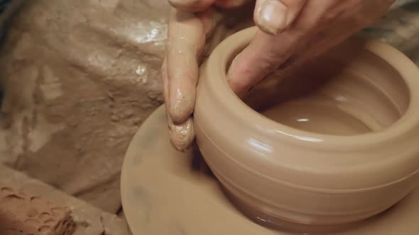 Apprentice learning clay pottery on ancient kick operated revolving wheel