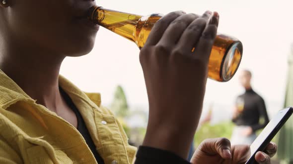 Young African American woman drinking a beer on a rooftop