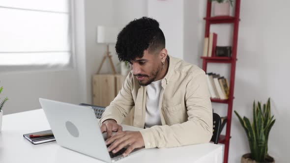 Concentrated Young Latino Man Working on Laptop From Home