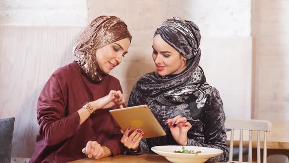 Two Pretty Muslim Woman Use Tablet in Cafe