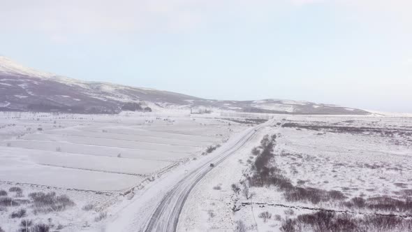 Aerial View Of Car Driving Through Snowy Road At Winter.