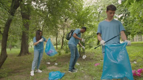 Multiracial Group of Young Volunteers Using Litter Sticks Outdoors