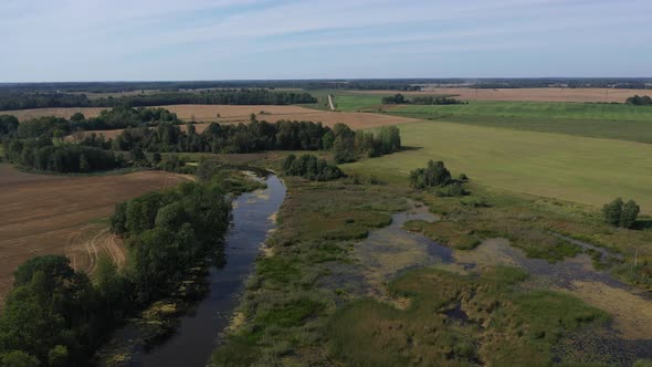 Aerial view of Green and Scenic Latvian Countryside with a river an farm field