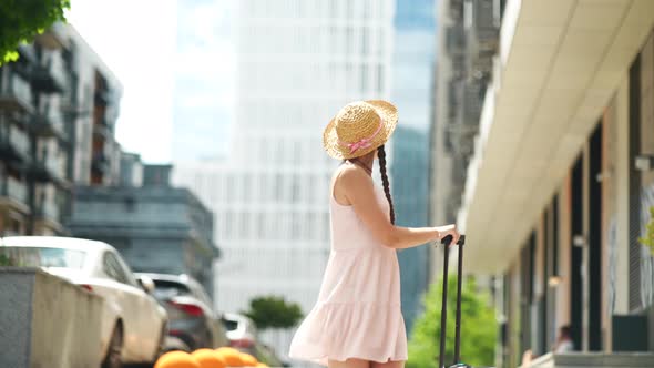 Young Woman Walks with a White Suitcase on the Street