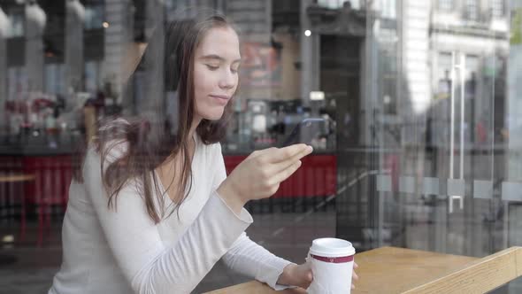 Young woman in a cafe enjoying a coffee and using a smartphone - Beautiful br