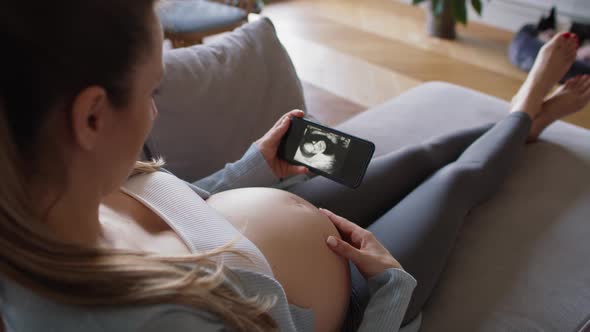 Pregnant woman looking on medical scans on the smartphone. Shot with RED helium camera in 8K
