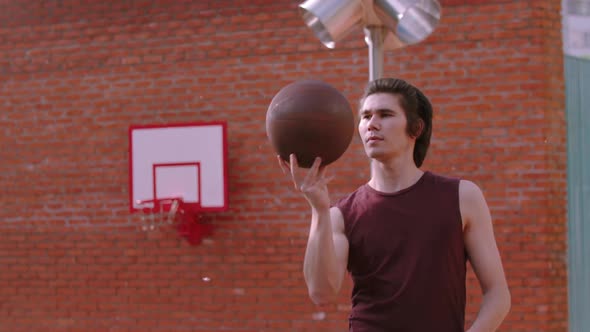 Young Handsome Man Spinning Basketball Ball on the Finger