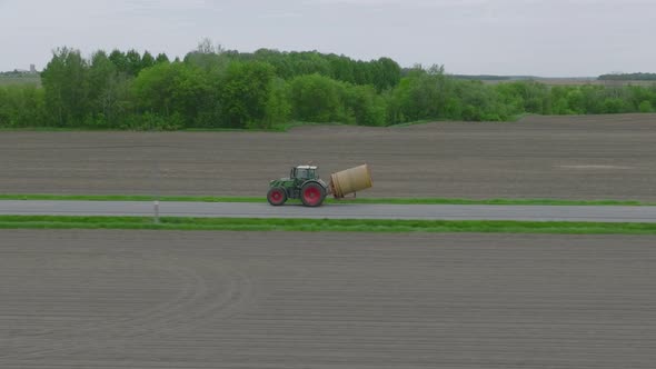 Farm Tractor Traveling On A Countryside Road. Aerial Tracking Shot