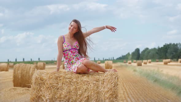 Girl Sitting on Hay Ball on Agricultural Field