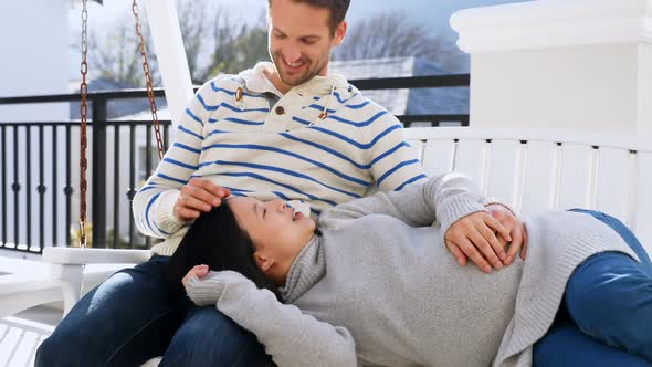 Pregnant couple relaxing in swing 