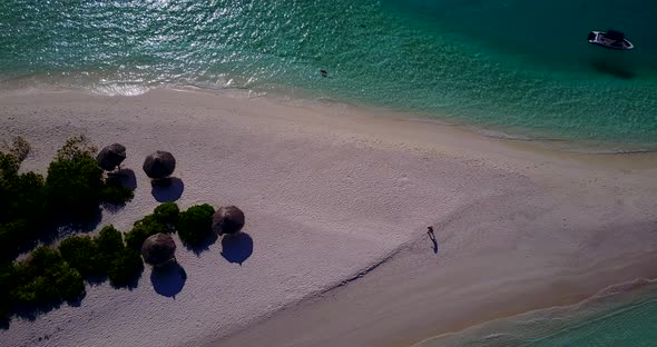 Wide above travel shot of a paradise sunny white sand beach and aqua blue water background in 4K