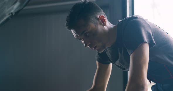 Close Up Portrait of Disappointed Auto Mechanic Examining Vehicle Engine at Repair Station