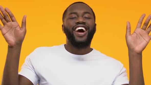 Happy African-American Man Dancing and Having Fun on Yellow Background, Close-Up