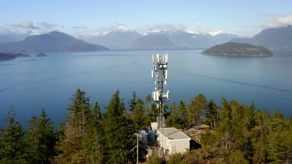 Towering Cell Site In A Verdant Environment With Placid Seascape And Distant Mountain View In Horses