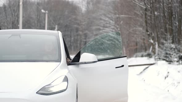 Stylish Woman in Fur Coat Sitting Into the White Gybrid Car