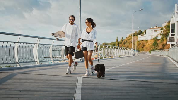 Millennial Spouses Walking with Dog and Keeping Skateboards Slow Motion