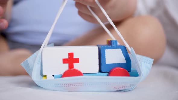 Child Boy Holds an Ambulance Toy Wooden