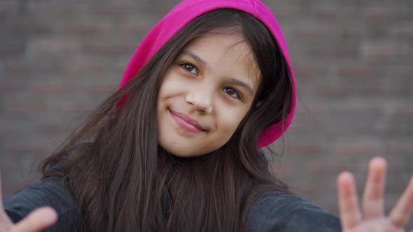 Portrait of a Cheerful Brunette Girl on a Brick Wall Background