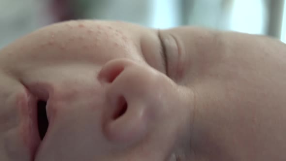 A close up of a sleepy, relaxed newborn baby's face.  Shot in high speed photography.
