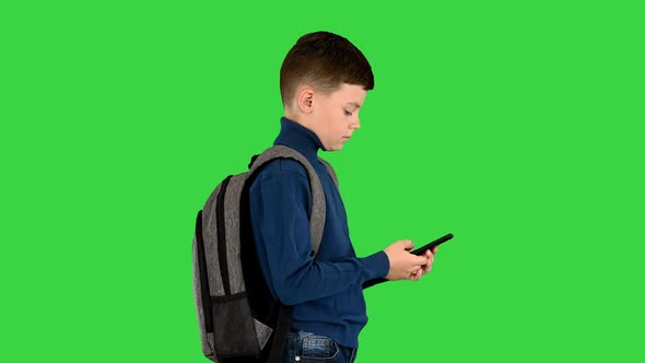 Schoolboy with a Backpack Using Mobile Phone on a Green Screen Chroma Key