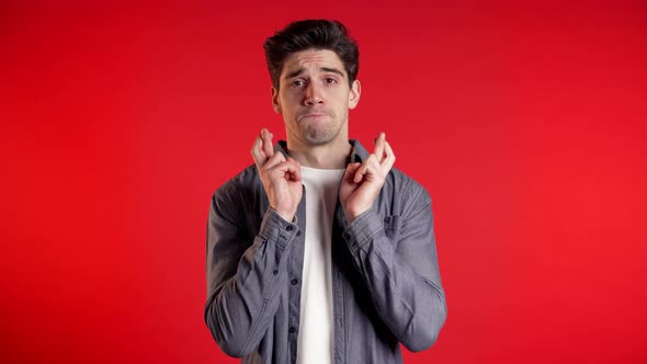 Handsome Man in Shirt Praying Over Red Background. Guy Begging Someone.