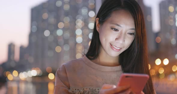 Woman use of mobile phone in city in the evening