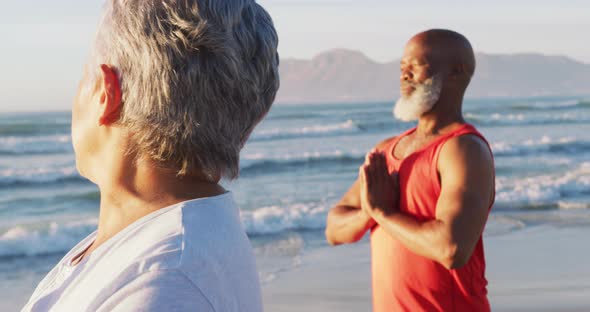 Senior african american couple practising yoga at the beach