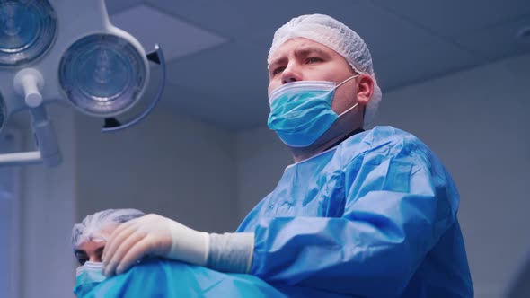 Portrait of male surgeon. Doctor in mask and protective uniform looking ahead seriously.