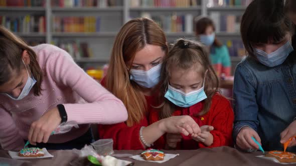 Masked Teacher and Autistic Girl Decorating Cookie