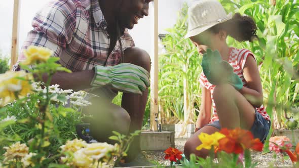 African american father and daughter gardening and giving a high five