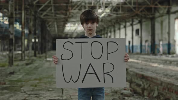 School Aged Boy with Stop War Banner Standing on Plant