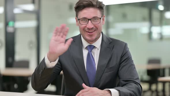 Cheerful Middle Aged Businessman Waving at the Camera