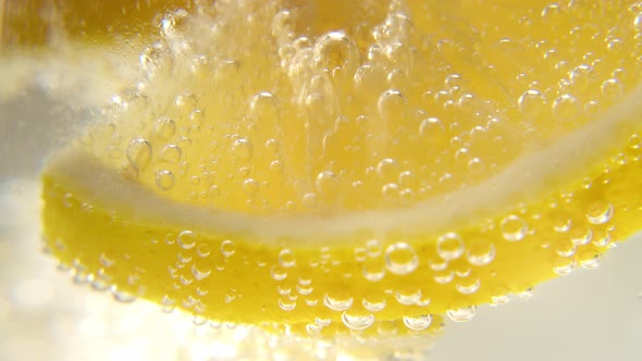 Fresh Lemon is Added to a Glass of Sparkling Ice Water Making a Refreshing Soft Drink