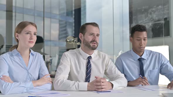 Middle Aged Businessman Giving Presentation with Assistants on Office Table