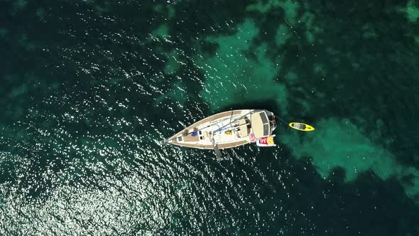 Aerial view above sailboat swinging on the coast of Varko, Greece.