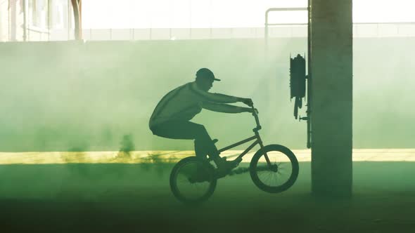 BMX rider in an empty warehouse using smoke grenade