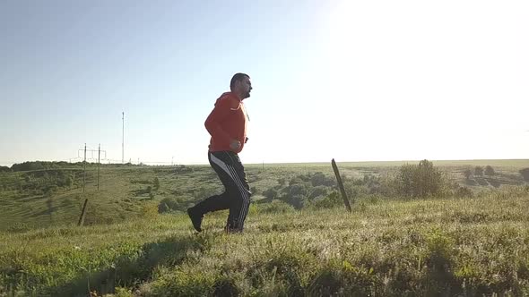 Slow motion footage of a young man running in blooming fields.