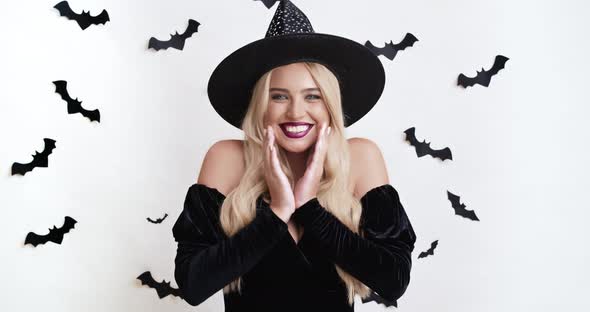 Studio Portrait of Amazed Blonde Witch Enjoying Halloween Surprise, Cheering at Camera