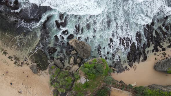 Top down aerial view of giant ocean waves crashing and foaming in coral beach