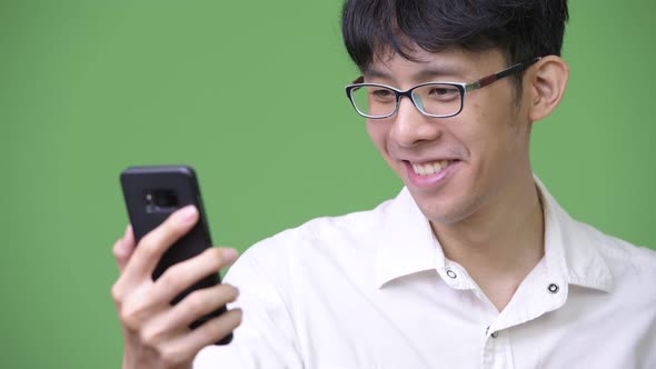 Happy Young Asian Businessman Smiling While Using Phone