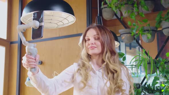 Smiling Woman Holding Selfie Stick with Modern Phone