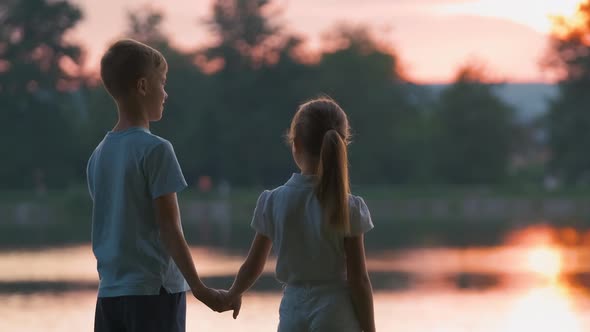 Happy Siblings Standing Together Holding Hands in Summer Park
