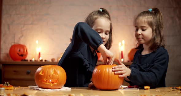 Two Cute Little Girls Are Cutting a Pumpkin on the Table for Halloween
