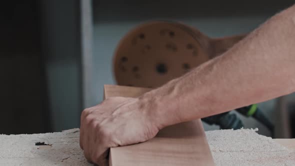 Man Worker Makes the Side of a Rectangular Wooden Detail Softer with a Grinding Machine