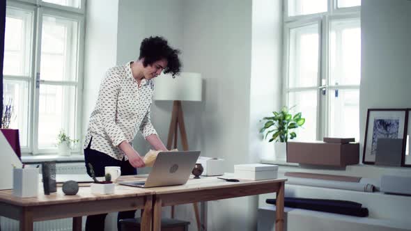 Young online shop owner packing box with items ordered by client