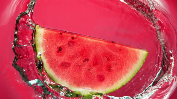 Super Slow Motion Shot of Falling Fresh Watermelon Slice Into Water on Red Background at 1000Fps.