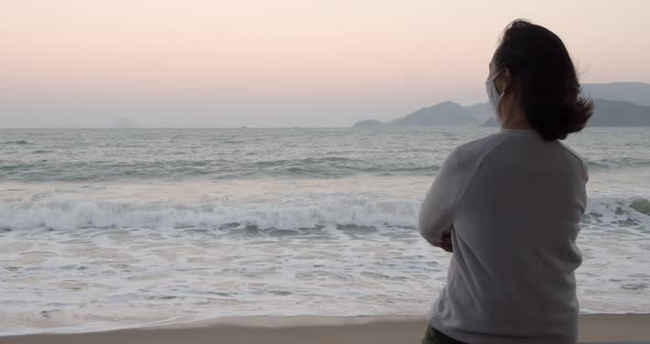 An Aged Woman Wearing a Protective Mask Is Doing Exercises and the Sea View Wearing a Covid19 Mask