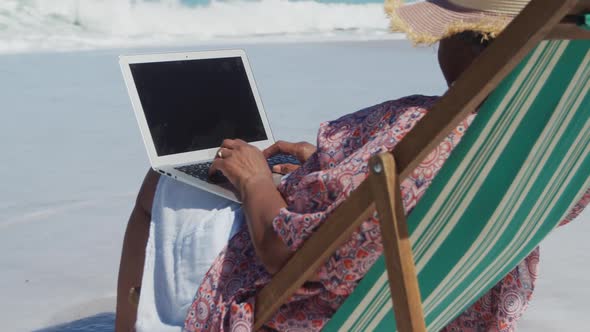Senior woman using laptop at the beach