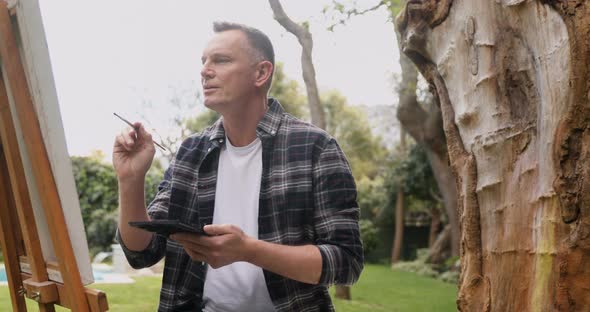 Man painting on canvas in the garden 4k